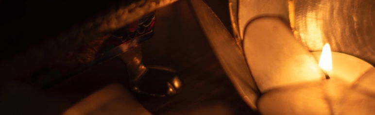close up image of candle flame in a lotus flower candle holder on the right side of the image