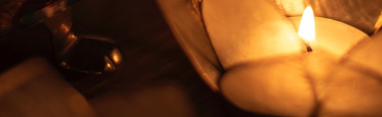 close up of lotus candle holder with lit candle on black screen