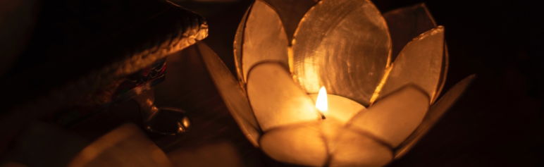 close up of lotus candle holder with lit candle on black screen