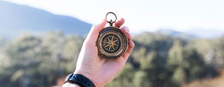 close up of masculine hand holding a compass